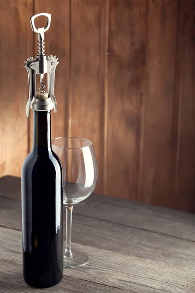 Uma garrafa de vinho é um saca-rolhas e um copo na velha mesa de madeira — Fotografia de Stock