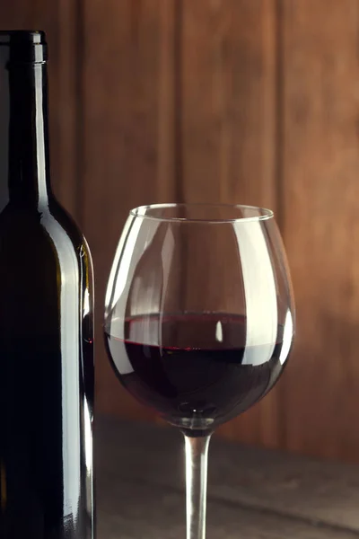 Botella de vino y una copa sobre una vieja mesa de madera — Foto de Stock