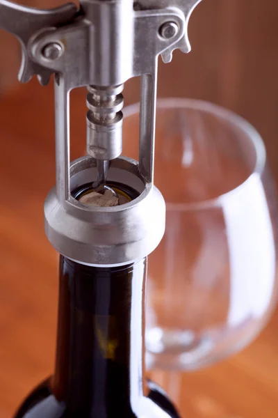 Corkscrew and a glass of wine on an old wooden table — Stock Photo, Image