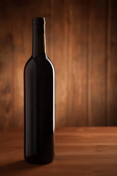 Láhev vína na starý dřevěný stůl — Stock fotografie