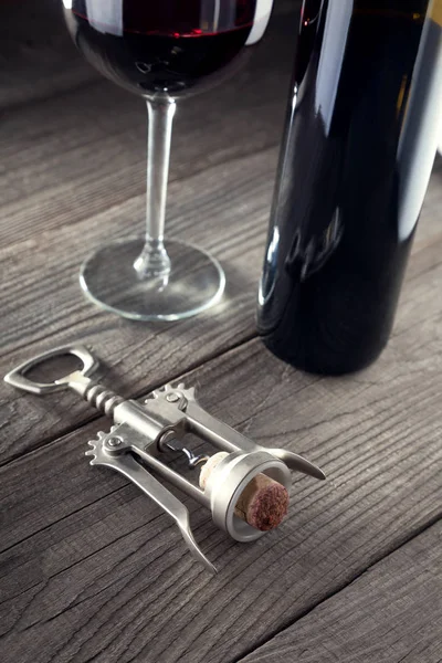 Corkscrew e um copo de vinho em uma mesa de madeira velha — Fotografia de Stock
