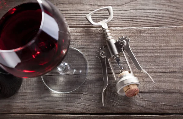 Corkscrew e um copo de vinho em uma mesa de madeira velha — Fotografia de Stock