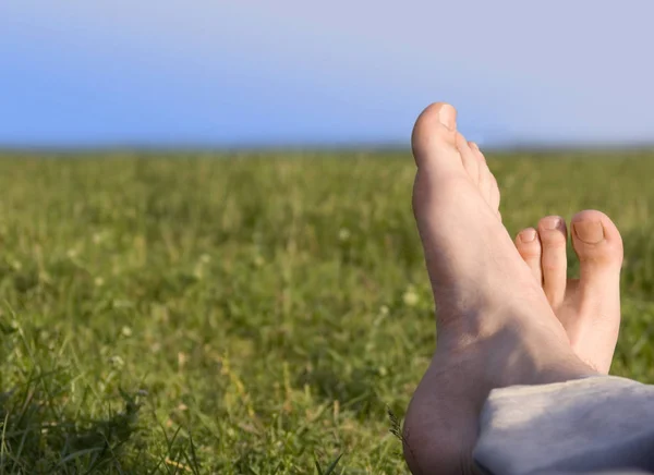 Bara fötter vilar på gräs i soliga sommardag för män under våren — Stockfoto