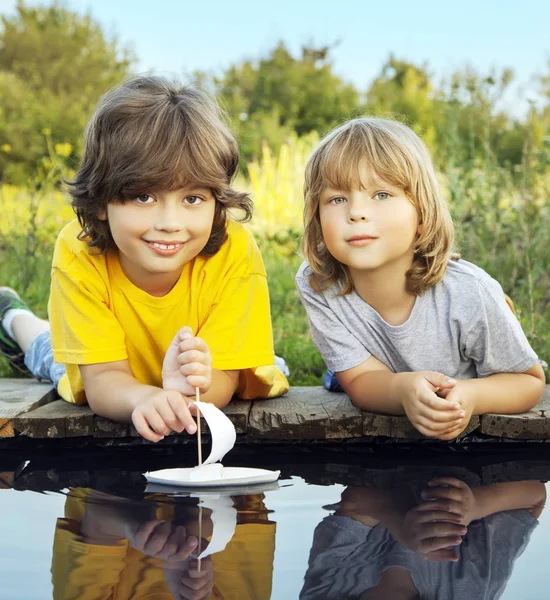 Dwóch chłopców dozwolone papieru łodzie z przystani rzeki — Zdjęcie stockowe