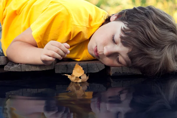 Boy play with autumn leaf ship in water, chidren in park play wi — Stock Photo, Image