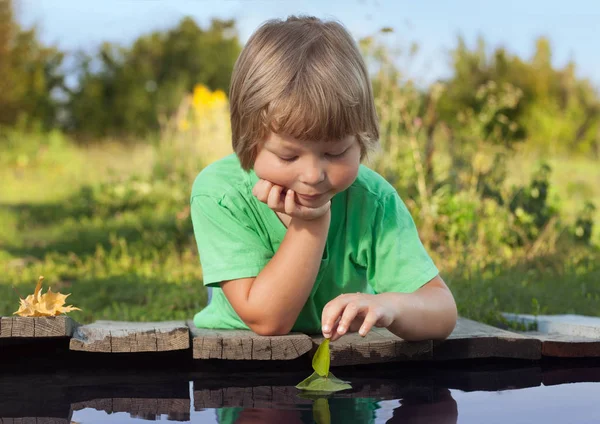 Folha-navio verde em crianças mão na água, menino no parque brincar com — Fotografia de Stock