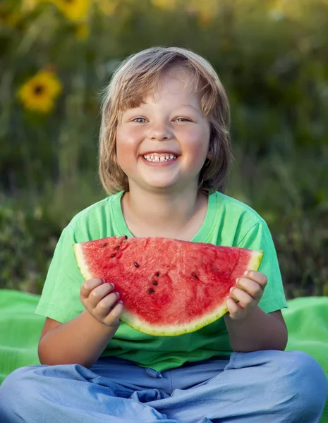 Glückliches Kind, das Wassermelone im Garten isst. Junge mit Obst im Freien — Stockfoto
