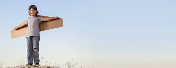 Niño feliz con cajas de cartón de alas contra el cielo sueño de volar —  Fotos de Stock