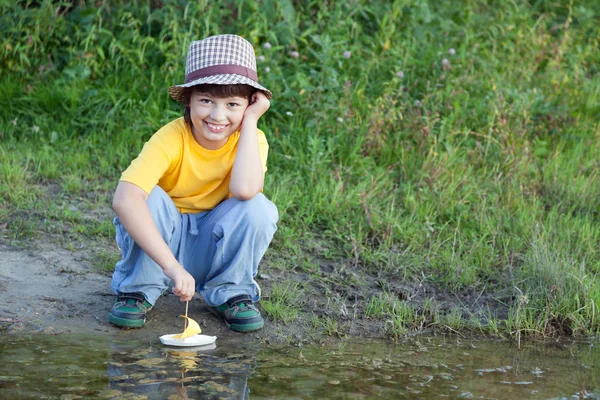 Chłopiec gry z jesiennych liści statku w wodzie, dzieci w parku grać wi — Zdjęcie stockowe