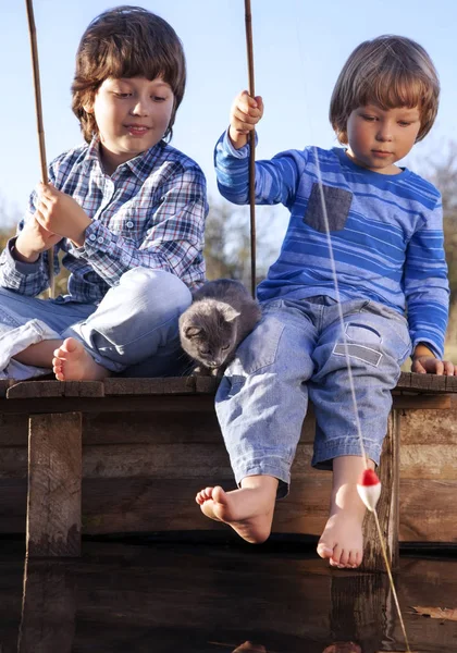 Glada pojkar fiska på floden, två barn av fisherma — Stockfoto