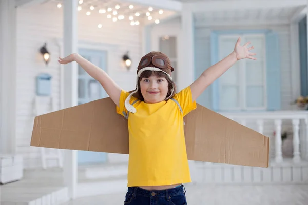 Niño feliz con cajas de cartón de alas en casa sueño de volar —  Fotos de Stock
