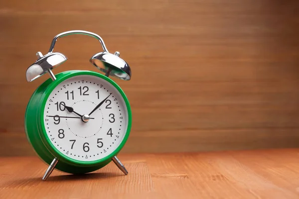 Clássico relógio de alarme verde manhã tempo de despertar no backgroun de madeira — Fotografia de Stock