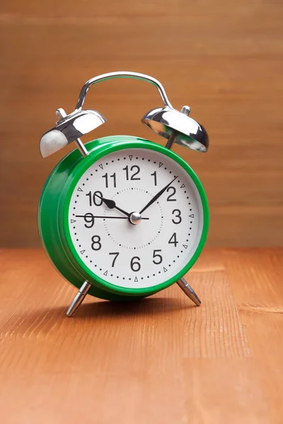 Κλασικό πράσινο ξυπνητήρι το πρωί ώρα αφύπνισης στο ξύλο backgroun — Φωτογραφία Αρχείου