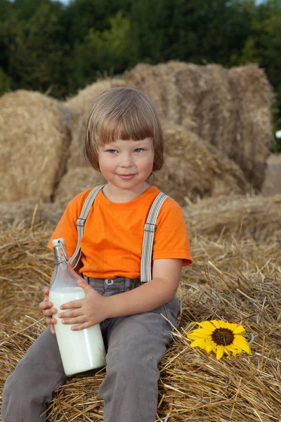 Child on a haystack with bread and milk — Stock Photo, Image