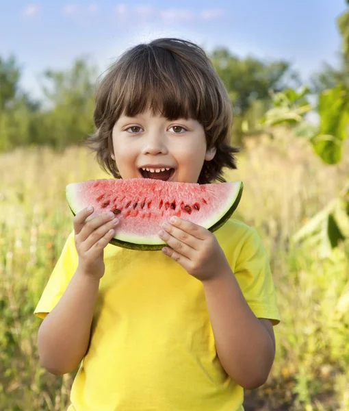 Criança feliz comendo melancia no jardim — Fotografia de Stock