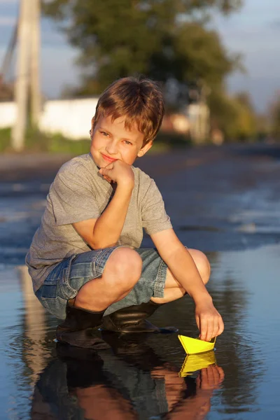 Junge spielen mit herbstlichem Papierschiff im Wasser, Kinder im Park spielen mit — Stockfoto