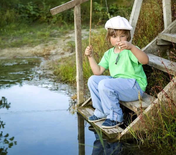 Lycklig pojke fiska på floden, en barn fiskare med en — Stockfoto