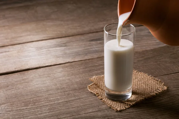 Jarra de leche con una mesa de campo viejo, una bebida blanca se vierte i —  Fotos de Stock