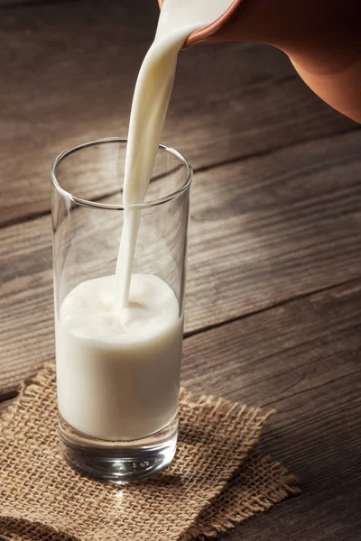 Brocca di latte con un vecchio tavolo di campagna, una bevanda bianca viene versata i — Foto Stock