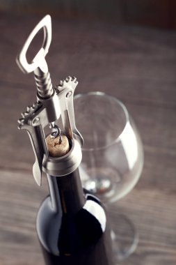 Corkscrew and a glass of wine on an old wooden table clipart
