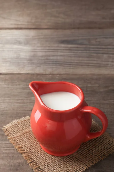 Milk in glass pitcher on white background wooden table