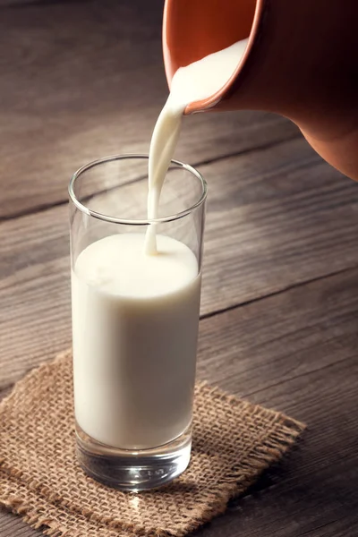 Jarra de leche con una mesa de campo viejo, una bebida blanca se vierte i —  Fotos de Stock