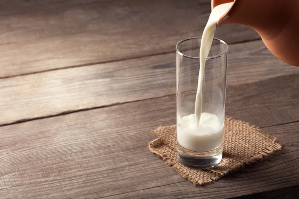 Milchkrug mit einem alten Landtisch, ein weißes Getränk wird ausgeschenkt. — Stockfoto