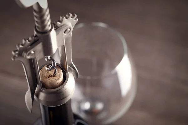 Corkscrew e um copo de vinho em uma mesa de madeira velha — Fotografia de Stock