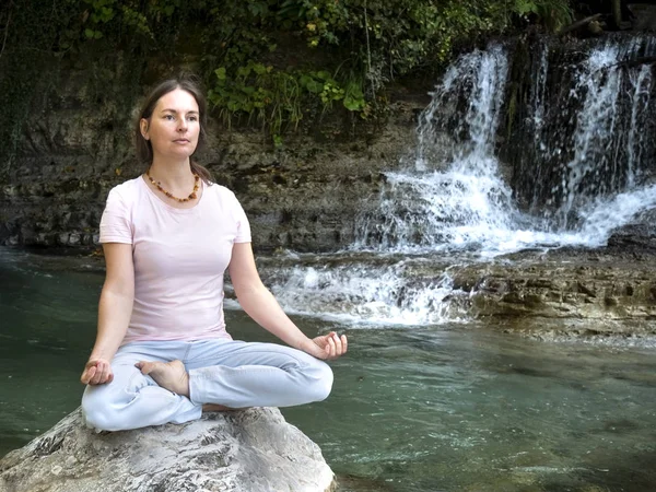 Mulher está praticando ioga em pose de lótus no lago de depósito de montanha — Fotografia de Stock