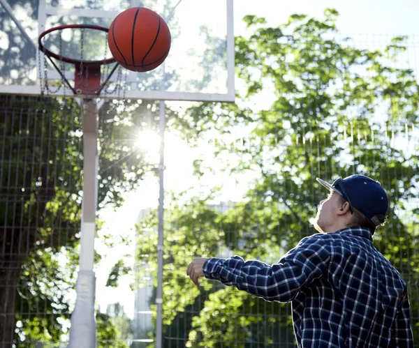 Мальчик играет в баскетбол на открытом воздухе на спортивной площадке — стоковое фото