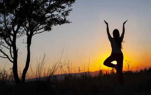 Yoga tree pose by woman silhouette with sunset. Virabhadrasana, — ストック写真