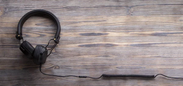 Nowoczesne słuchawki z długim kablem na tle drewna, Muzyka onli — Zdjęcie stockowe