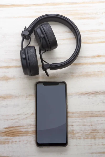 Auriculares modernos con Smartphone sobre fondo de madera, Música onli — Foto de Stock