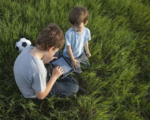 Δύο παιδιά, χρησιμοποιώντας την οθόνη αφής δισκίο pc στο γρασίδι — Φωτογραφία Αρχείου