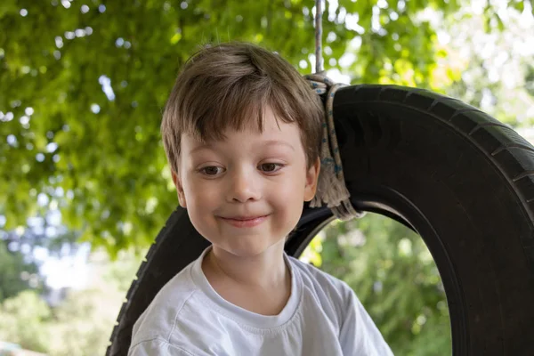 Happy Boy brincando em uma roda de balanço no jardim. Verão ensolarado d — Fotografia de Stock