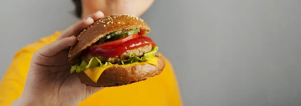Child eats burger on grey background. Male child with hamburger — 스톡 사진