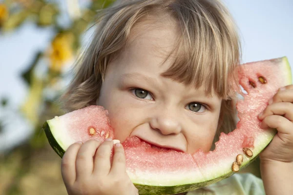 庭でスイカを食べて幸せな子。屋外の果実を持つ少年 — ストック写真