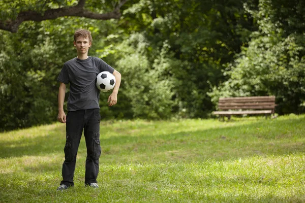 Teen dětský fotbalista. Fotbalový chlapec s míčem na zelené trávě. — Stock fotografie