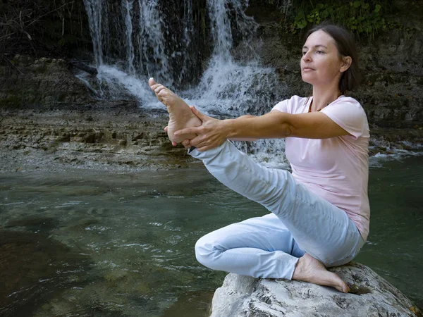 Mulher está praticando ioga em pose de lótus no lago de depósito de montanha — Fotografia de Stock