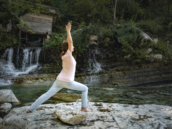 年轻女子正在高山湖畔的荷花中练习瑜伽 — 图库照片