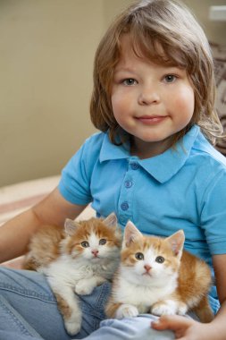 Elinde iki kırmızı kedi yavrusu olan küçük çocuk yaklaş. En iyi arkadaşlar. Çocukların evcil hayvanlarla etkileşimi.