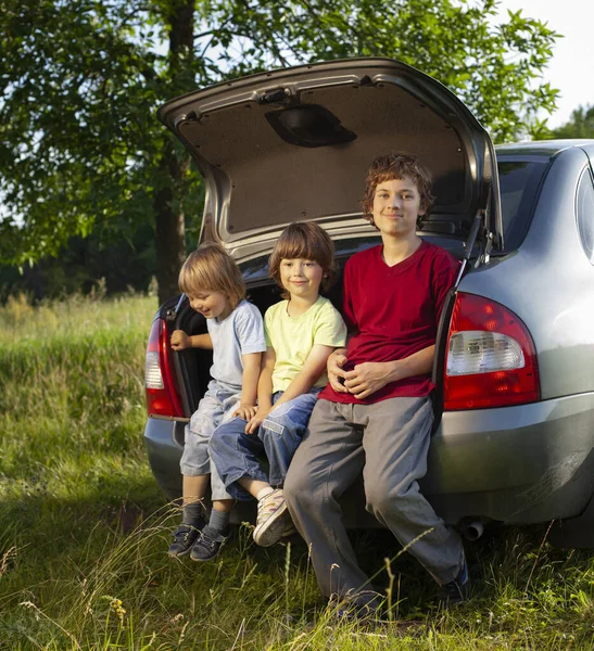 Neşeli Çocuk Dışarıda Bir Arabanın Bagajında Oturuyor — Stok fotoğraf