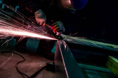 Öğütücüyle çalışan işçi fabrikada metal bir yüzeyi parlatıyor. Evet.