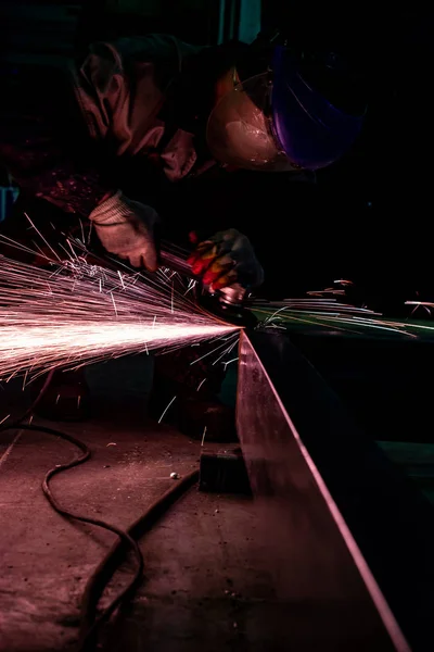 Работник с мельницей полирует металлическую поверхность на заводе. S — стоковое фото