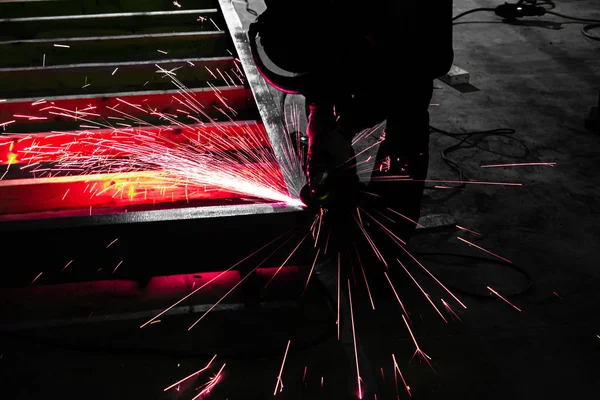 Работник с мельницей полирует металлическую поверхность на заводе. S — стоковое фото