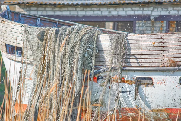 Μια παλιά βάρκα που ξεφλουδίζει στέκεται στην ακτή. Ένα δίχτυ αλιείας h — Φωτογραφία Αρχείου