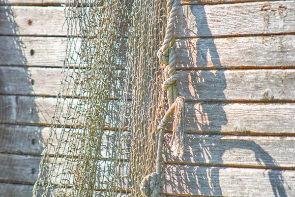 An old peeling fishing boat stands on the shore. A fishing net h — Stock Photo, Image