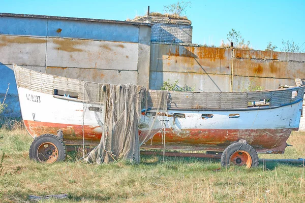 An old peeling fishing boat stands on the shore. A fishing net h — 스톡 사진