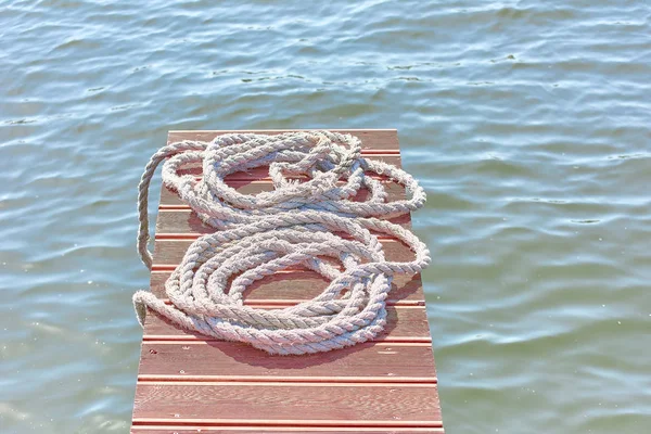 Vieja cuerda de amarre desgastada enrollada en una bahía se encuentra en una bri de madera — Foto de Stock