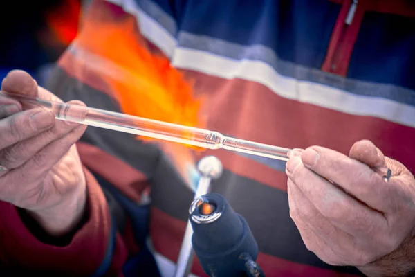 Närbild av händerna på en glasblåsare som arbetar på ett glasföremål — Stockfoto